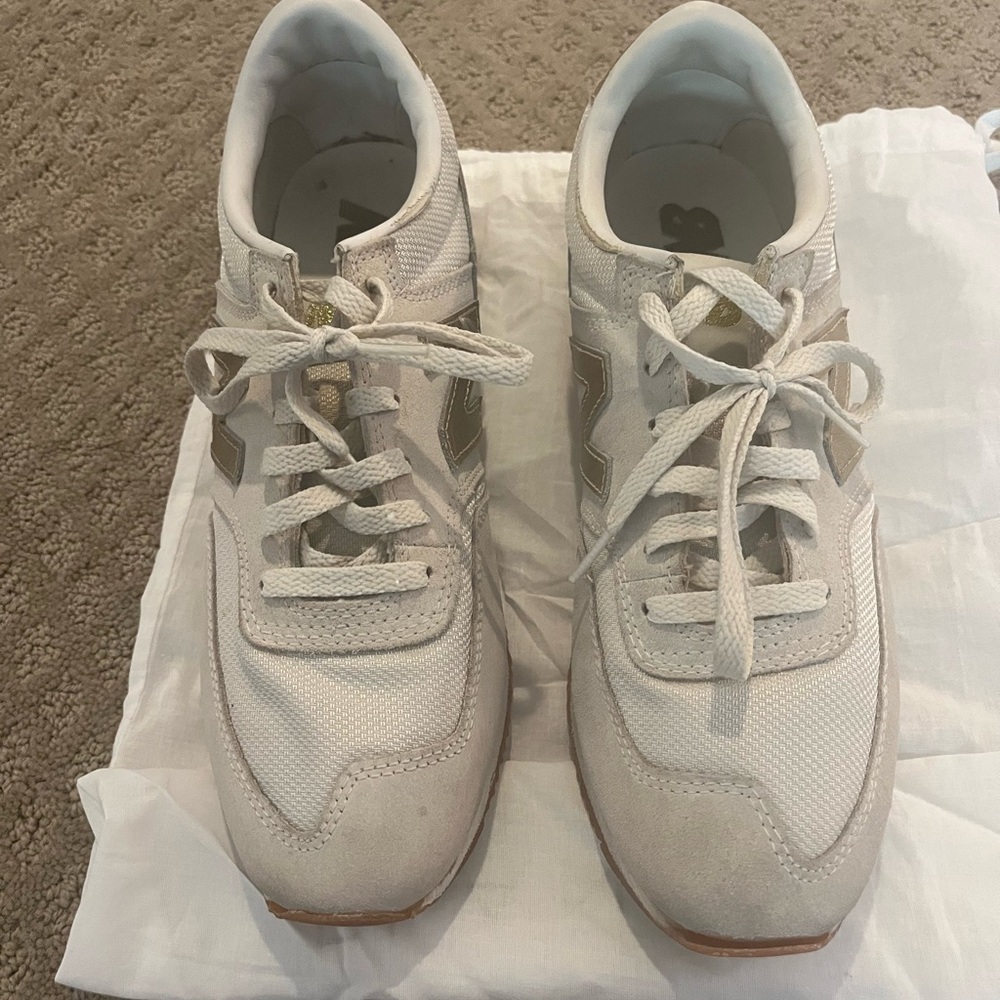 Woman’s New Balance white/ beige gold tennis shoes size 9.5